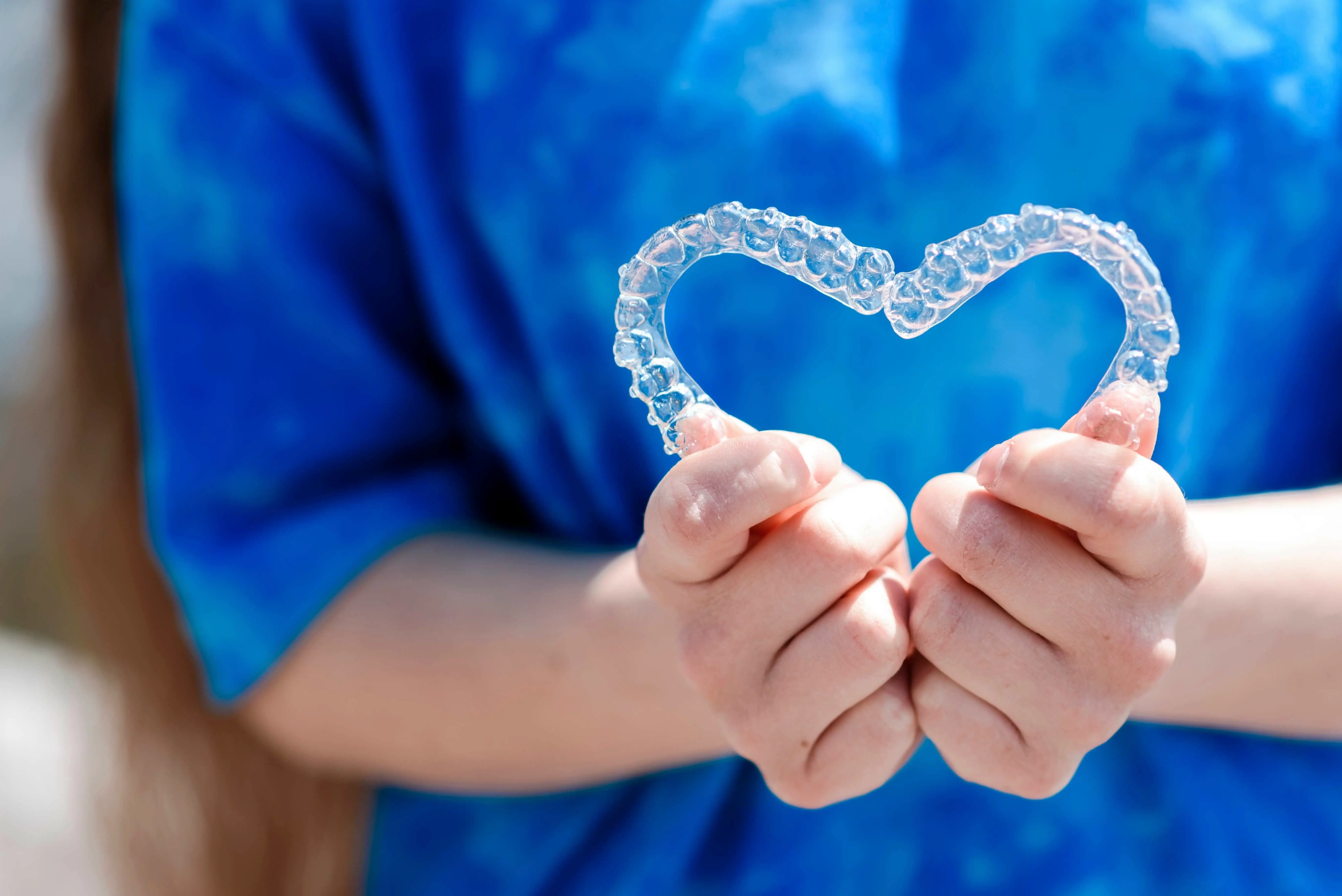 Adult wearing Invisalign clear aligners — barely visible on teeth